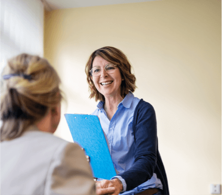 Smiling woman with glasses holding a clipboard