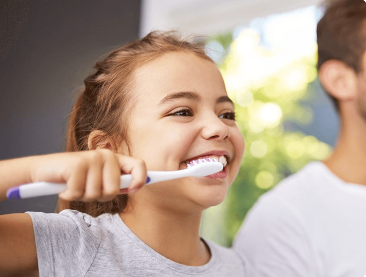 A little girl brushing her teeth with her dad